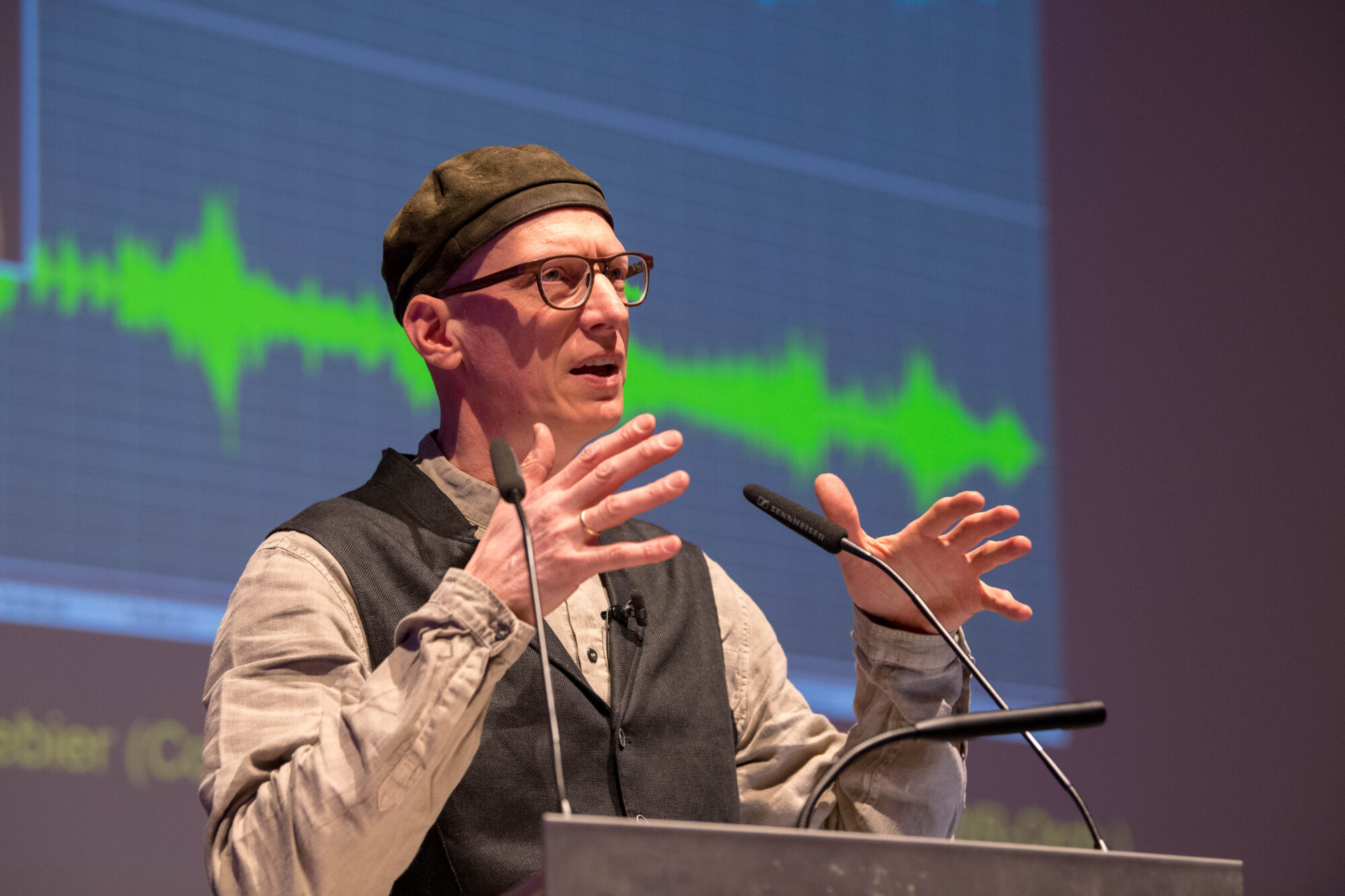 Martin Schleske is speaking into two microphones at a lectern.